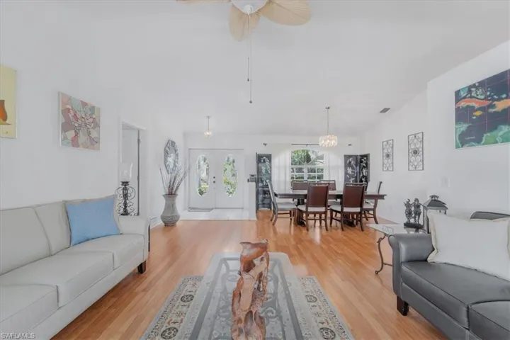 Living area featuring light wood finished floors, ceiling fan, and vaulted ceiling