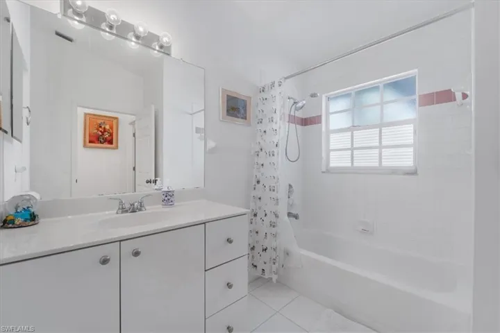 Full bath featuring shower / bath combo with shower curtain, vanity, and tile patterned floors