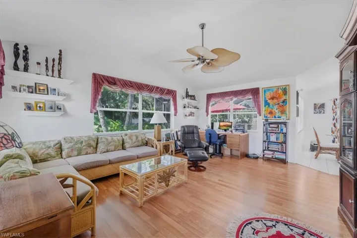 Living room featuring a ceiling fan, light wood-type flooring, and lofted ceiling
