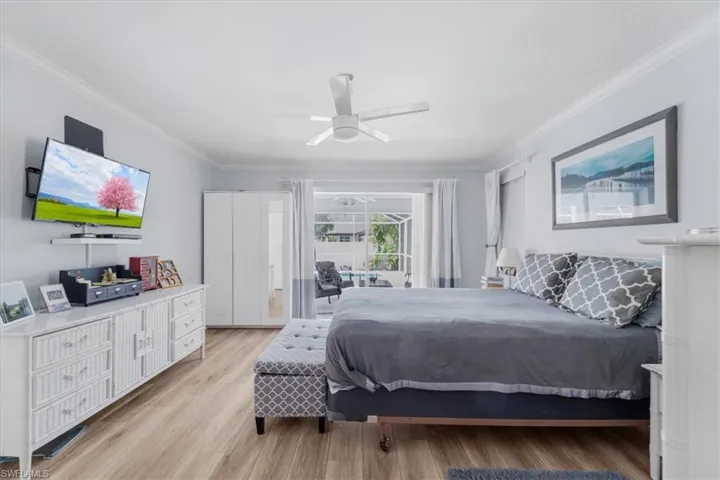 Bedroom with light wood finished floors, crown molding, and ceiling fan