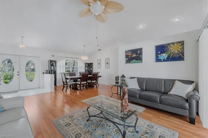 Living room with vaulted ceiling, ceiling fan, and wood finished floors