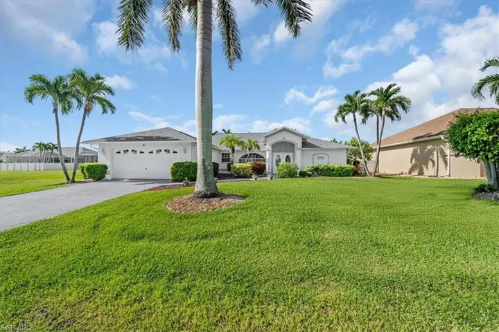 View of front of property featuring an attached garage, driveway, a front lawn, and stucco siding