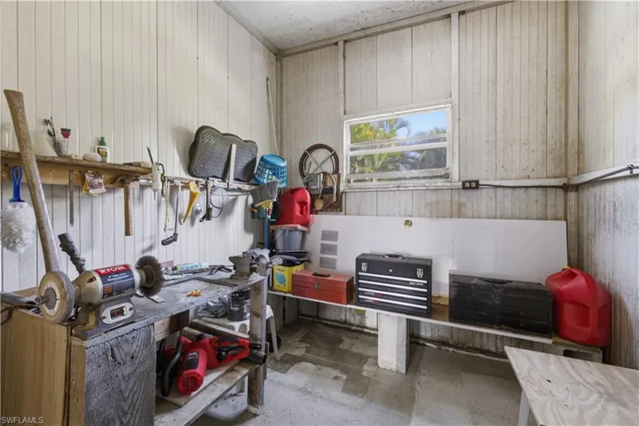 Utility room with a built-in workbench, wall-mounted shelving, and a horizontal window