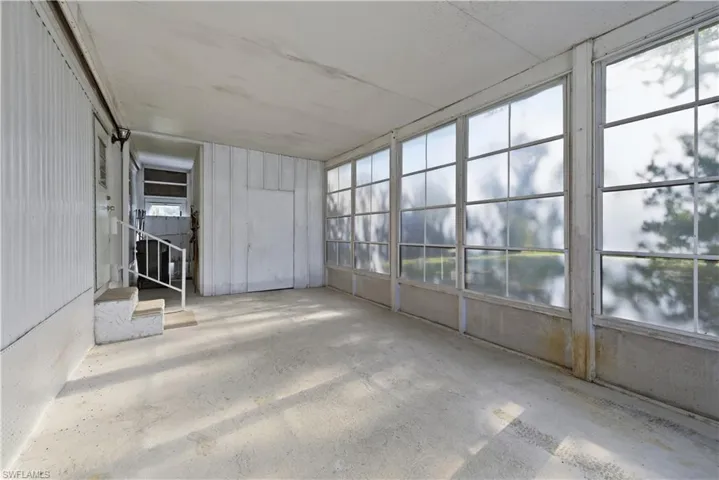 Enclosed porch featuring a row of large window panes and concrete flooring