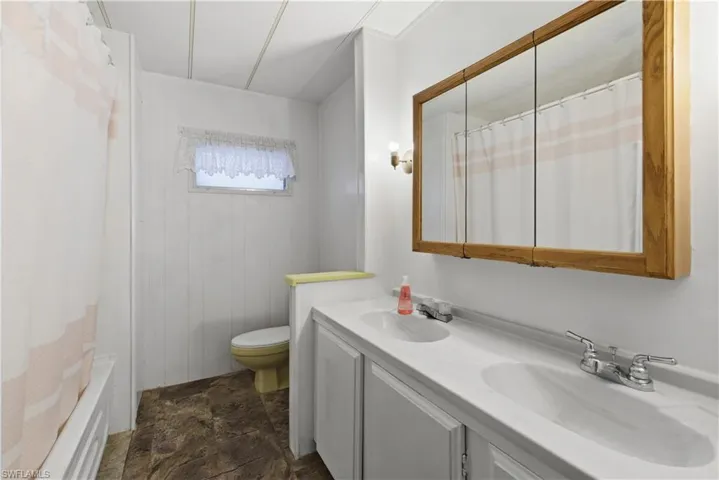 Dual vanity with integrated sinks, wood-finish medicine cabinet, and wall-mounted sconce lighting