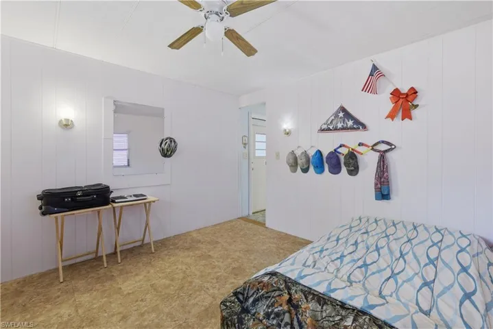 Bedroom featuring panel walls, wall-mounted light fixtures, a ceiling fan, and patterned floor covering