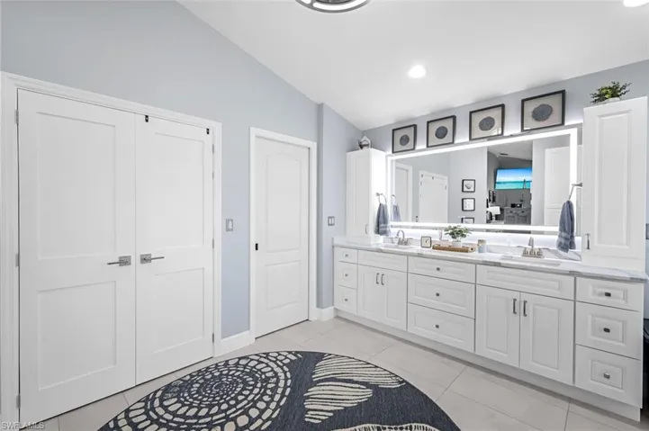 Bathroom with tile patterned flooring, a sink, lofted ceiling, and double vanity