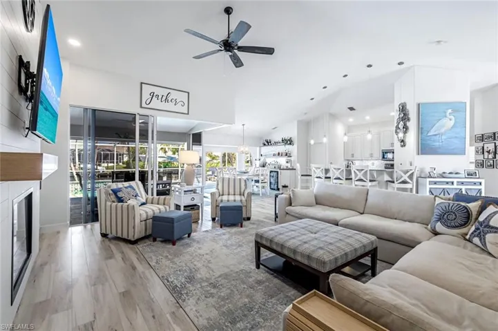 Living room featuring light wood-style floors, ceiling fan, a large fireplace, and recessed lighting