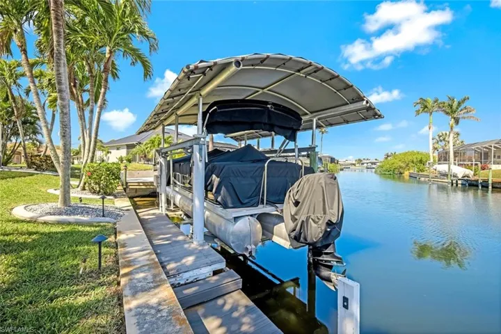 View of dock with a water view, a yard, and boat lift