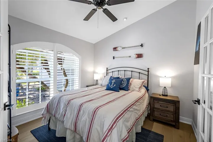 Bedroom featuring lofted ceiling, ceiling fan, baseboards, and wood finished floors