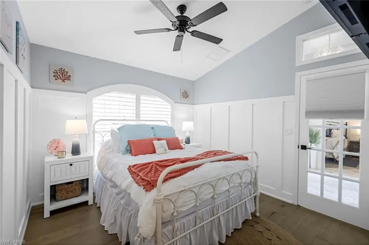 Bedroom featuring vaulted ceiling, wainscoting, wood finished floors, and visible vents