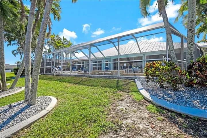 Rear view of property featuring a yard, a lanai, and metal roof