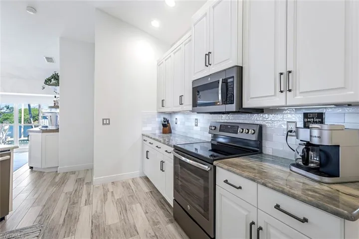 Kitchen with visible vents, white cabinets, appliances with stainless steel finishes, decorative backsplash, and dark stone countertops