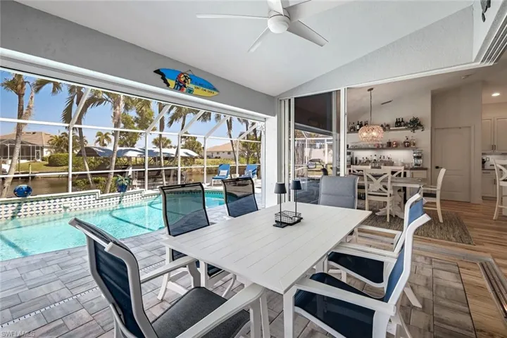 Pool with ceiling fan, glass enclosure, outdoor dining area, and a patio