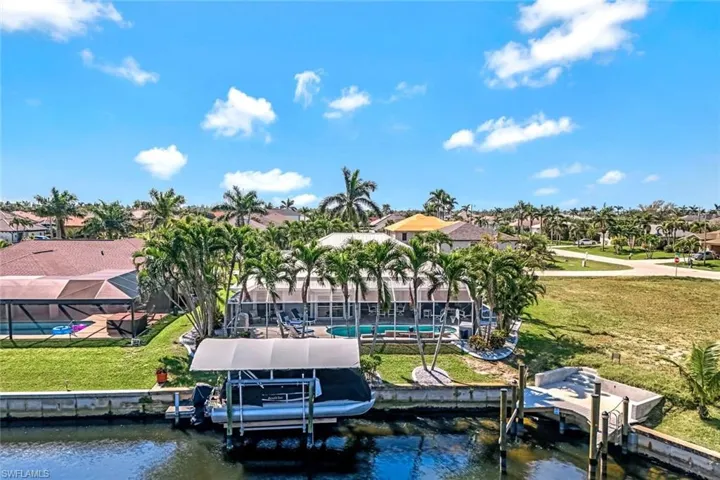 View of dock with glass enclosure, a water view, a lawn, and boat lift