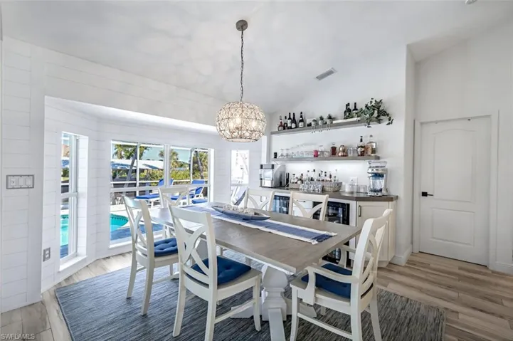 Dining space with light wood-type flooring, an inviting chandelier, visible vents, and vaulted ceiling