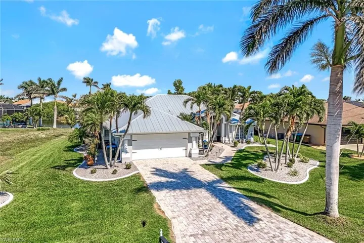 View of front of property with a front yard, decorative driveway, and an attached garage