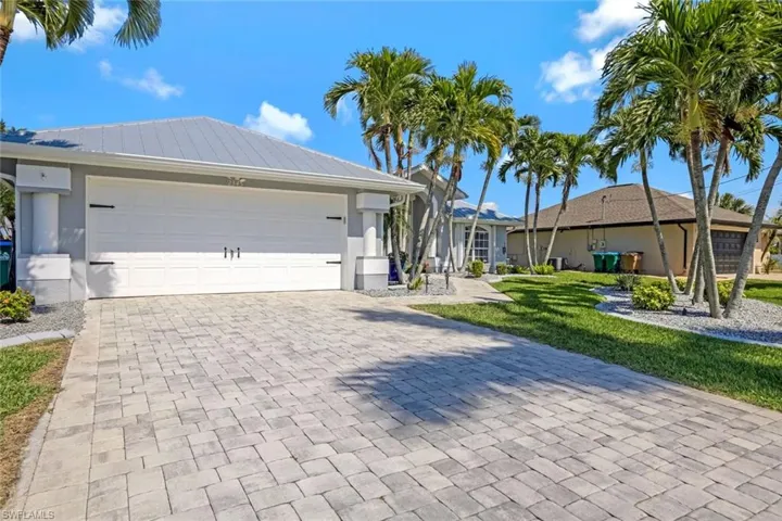 Single story home featuring a garage, metal roof, decorative driveway, and stucco siding