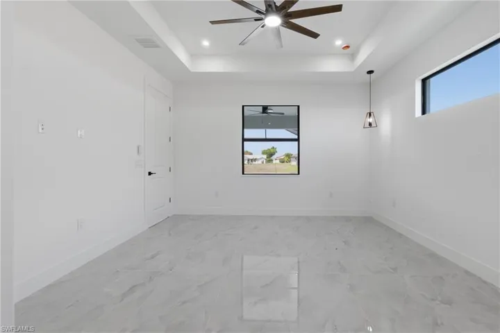 Spare room with a raised ceiling, recessed lighting, ceiling fan, and light marble finish floors