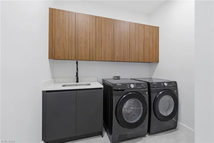 Laundry area featuring separate washer and dryer, cabinet space, and light tile patterned floors