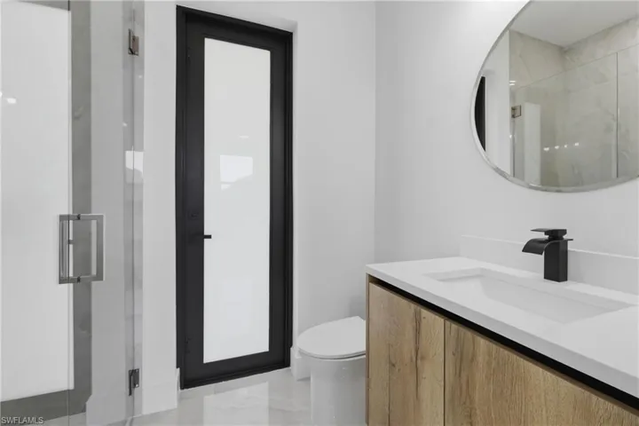 Full bathroom featuring vanity, a marble finish shower, and light marble finish flooring