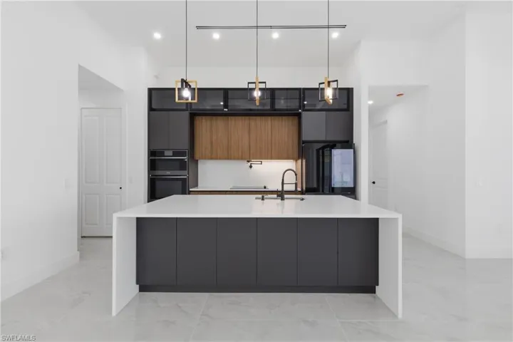 Two tone kitchen featuring modern cabinets, pendant lighting, dual tone cabinets, light stone counters, and double oven