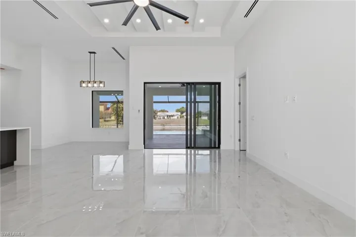 Unfurnished room with light marble finish floors, a high tray ceiling, a ceiling fan, and recessed lighting