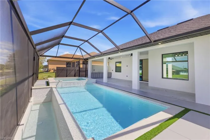 Combined pool / hot tub featuring a sunroom, a patio area, and glass enclosure