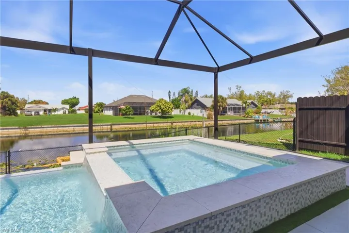 View of swimming pool with a water view, a residential view, an in-ground hot tub, and a fenced backyard