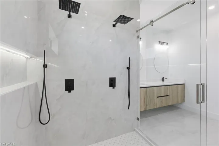 Bathroom featuring vanity and a marble finish shower
