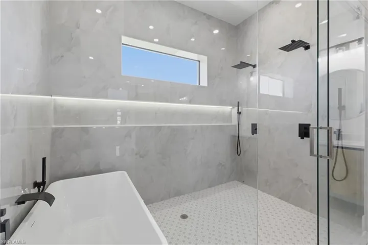 Full bathroom with a marble finish shower and a freestanding bath