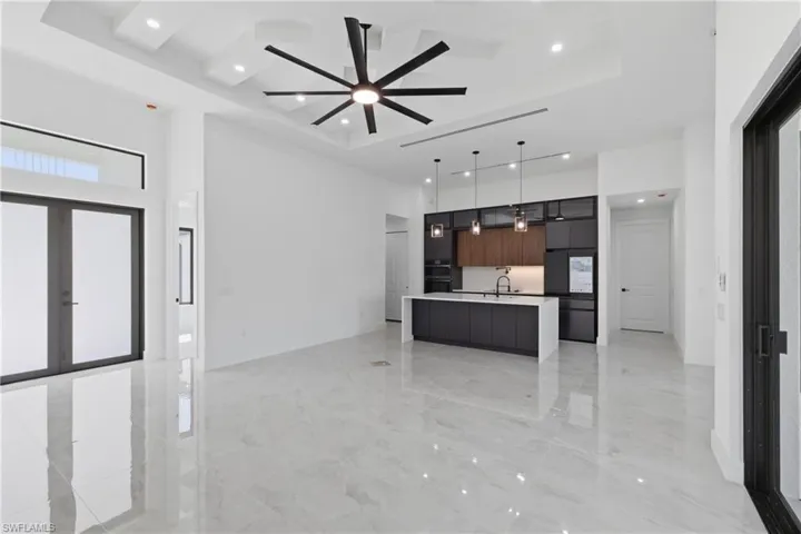 Unfurnished living room with a high tray ceiling, a ceiling fan, and recessed lighting