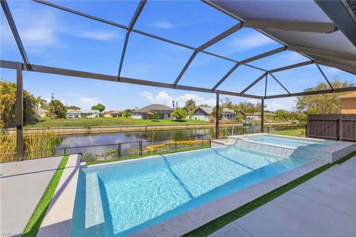 Integrated pool / spa featuring a residential view, a sunroom, glass enclosure, and a water view