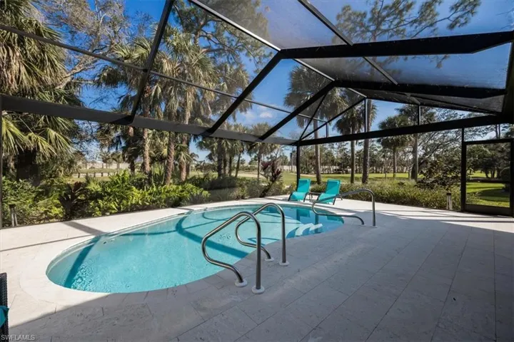 View of pool with glass enclosure and a patio area
