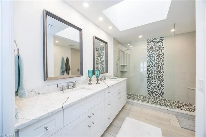 Bathroom with vanity, tiled shower, and a skylight