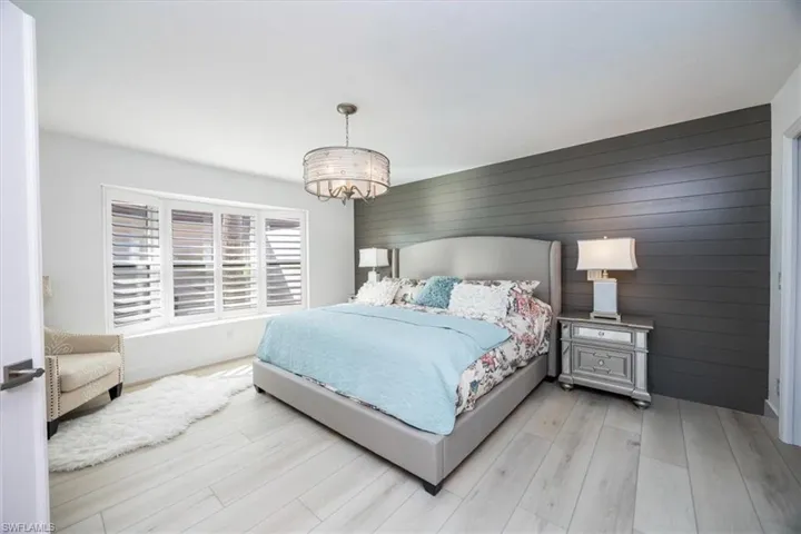 Bedroom featuring wooden walls, light wood-type flooring, and a notable chandelier