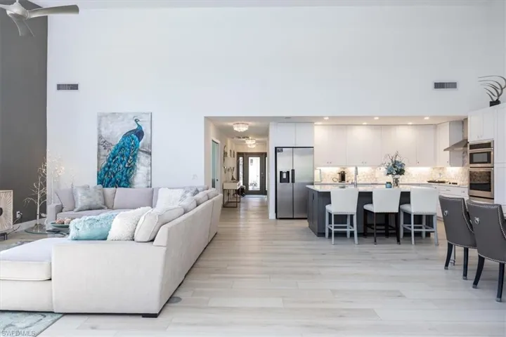 Living room with a high ceiling, light wood-type flooring, and an inviting chandelier