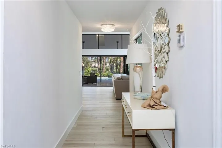 Hallway with hardwood / wood-style flooring and an inviting chandelier