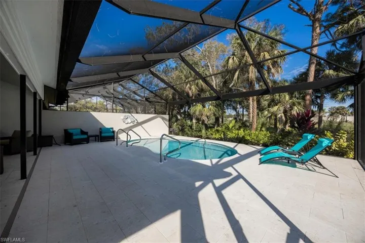 View of pool with glass enclosure and a patio area view of Golf green