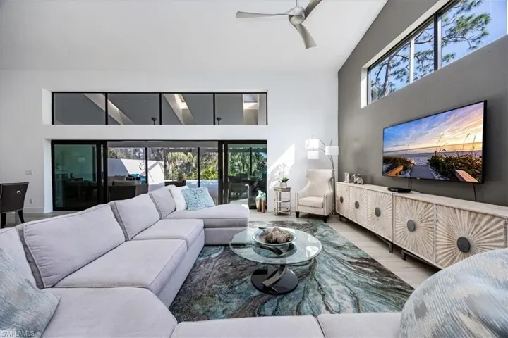 Living room featuring ceiling fan, plenty of natural light, hardwood / wood-style floors, and a high ceiling