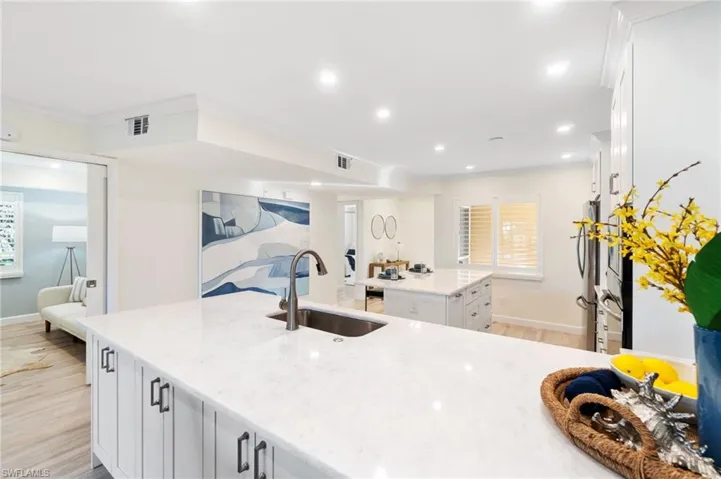 Large kitchen workspace with white marble counters, showing the entryway, front guest room, and the central den/3rd bedroom