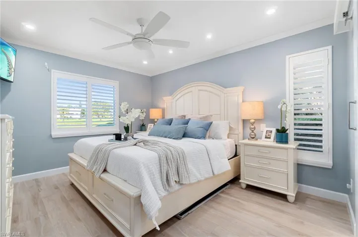Spacious primary suite features an abundance of natural light with golf course and lake views, while privacy is offered by plantation shutters.  Fresh paint, light, wood-like luxury vinyl flooring and crown molding enhance the spaciousness