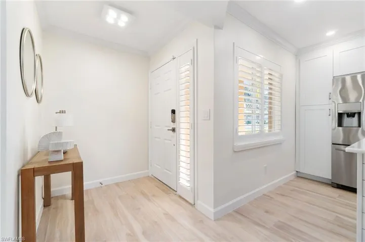 Entryway with light wood-style LVP floors and ornamental molding with new directional light fixture.