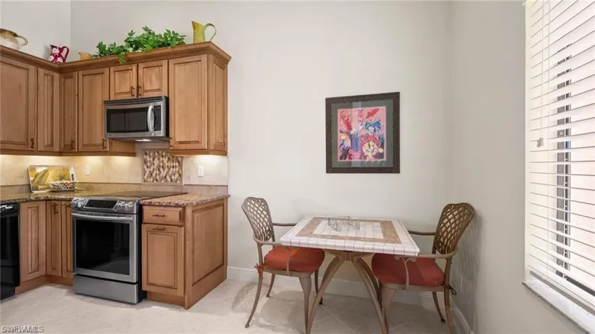 Kitchen with stainless steel appliances, light stone countertops, wood finish cabinetry, and light tile patterned floors