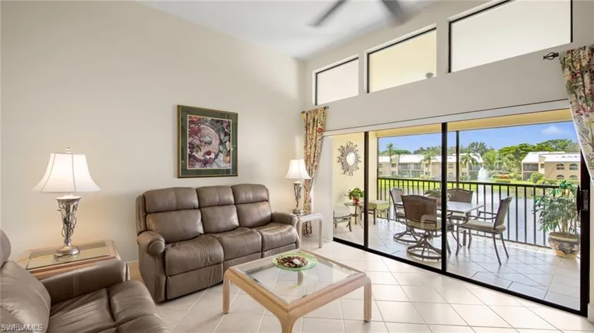 Tiled living room featuring plenty of natural light, a high ceiling, and a ceiling fan