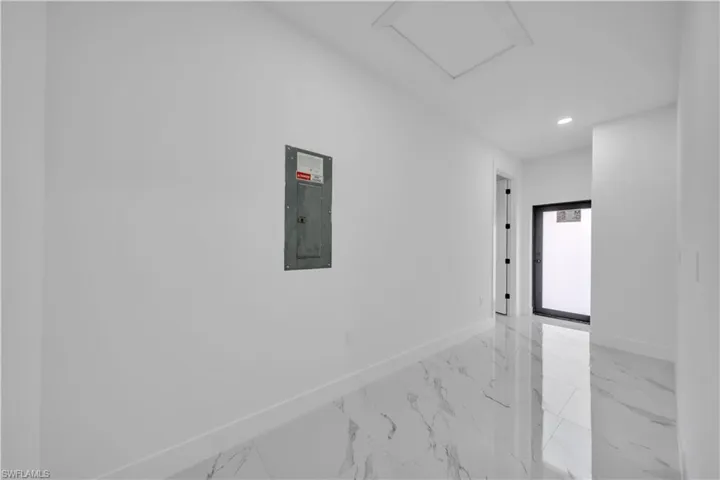 Corridor featuring recessed lighting, electric panel, and light marble finish floors