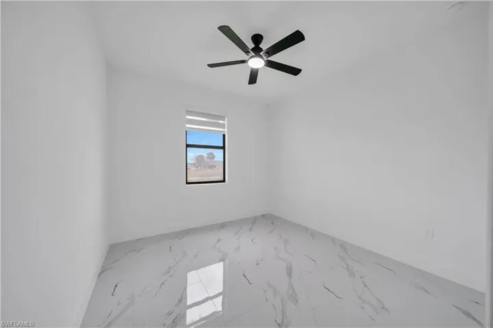 Empty room featuring light marble finish flooring and a ceiling fan