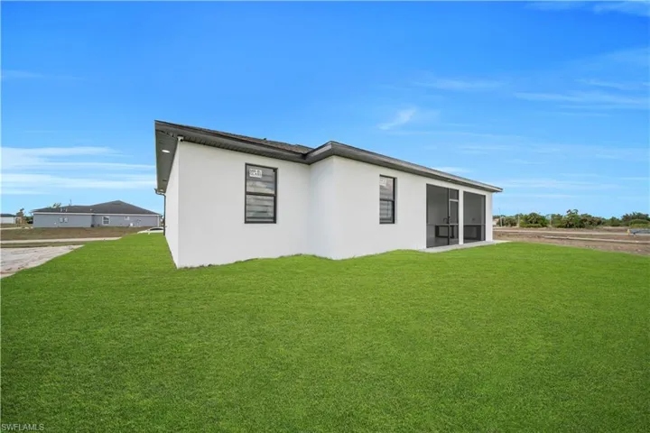Back of property with a lawn, stucco siding, and a sunroom