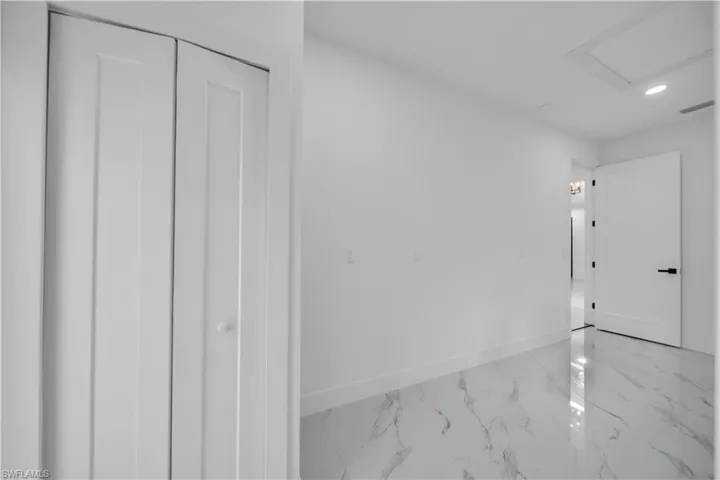 Unfurnished bedroom with recessed lighting, light marble finish floors, and a closet