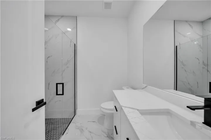 Bathroom with a marble finish shower, vanity, and marble finish flooring